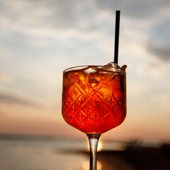 Aperol spritz cocktail in a tulip glass on a summer evening during sunset.