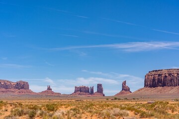 Peaceful desert landscape in a canyon with dry brown fields and rocky cliffs under a bright blue sky - Powered by Adobe