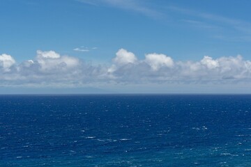 Blue sea waves under a blue sky with clouds.