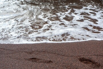 Fototapeta na wymiar Foamy water rolling into a sandy shore.
