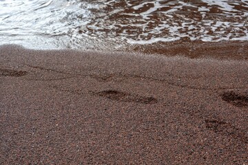 Foamy water rolling into a sandy shore.