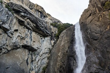 Waterfall flowing down the crag surrounded by a little vegetation