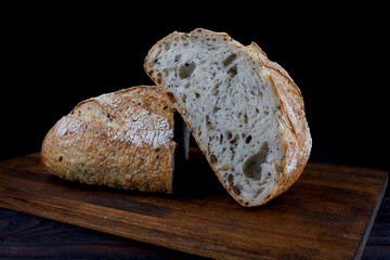 A loaf of designer bread cut in half with seeds on a wooden board. Art bread.