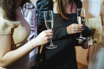Three women are clutching champagne glasses in their hands