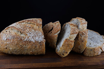 Cut loaf with seeds on a wooden board. Sliced pieces of bread. Art bread.
