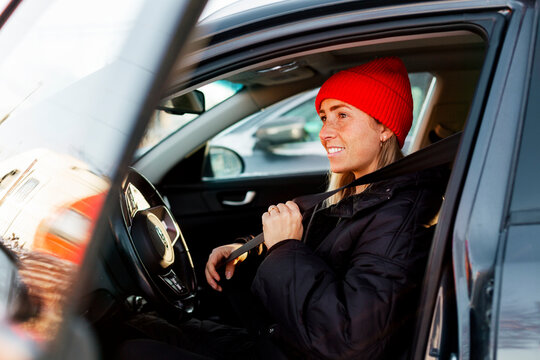 Contemplative woman fastening seat belt while sitting in car