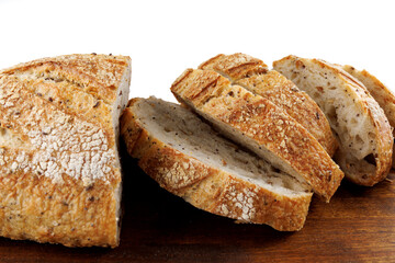 Cut loaf with seeds on a wooden board on a white background. Sliced pieces of bread. Art bread.