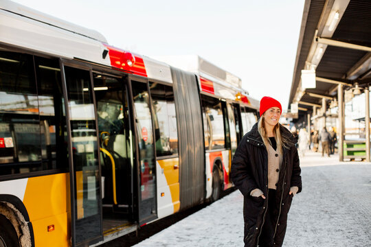 Woman with hands in pockets standing at bus stop
