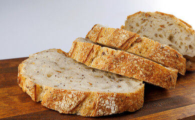 Cut loaf with seeds on a wooden board on a white background. Sliced pieces of bread. Art bread.