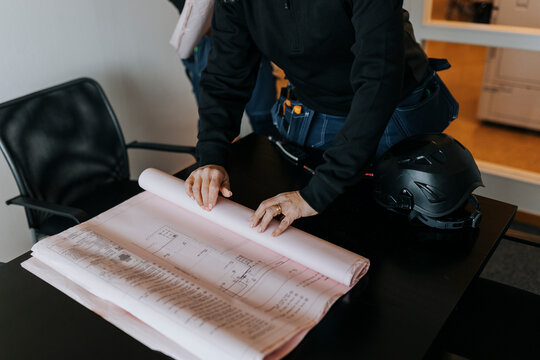 Mid section of person in office rolling up blueprint