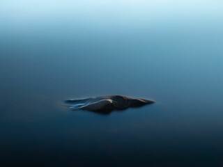 Closeup of water with a long exposure effect and stone in blurred background