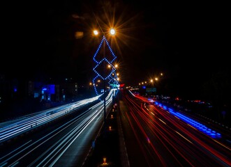 Long exposure shot of the road at night with lights of cars in the dark