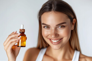 Fototapeta premium Radiant young woman with a gleaming smile presenting a skincare oil dropper bottle