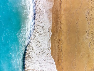 Fototapeta na wymiar Aerial view of ocean waves crashing on a sandy beach
