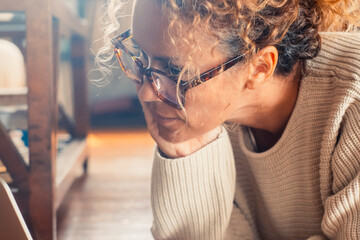 One young mature woman reading email or notification on laptop display wearing glasses and concentrated expression. People and internet small business connection lifestyle. Indoor online leisure - obrazy, fototapety, plakaty