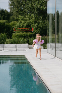Girl running near swimming pool on sunny day