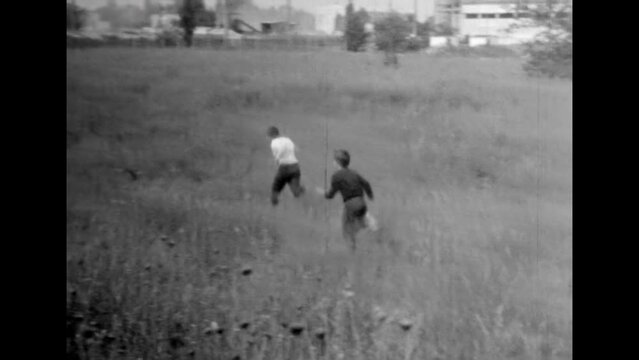 Children play catch on summer natural field. Happy children run around against sunny nature backdrop. Active carefree childhood. Kids running in fun game. Vintage black white film. Retro archive 1980s