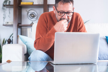 Contemplating adult boomer serious man looking away sitting on couch. Thoughtful pensive handsome serious male worker thinking about new idea or project analysing planning making decision concept