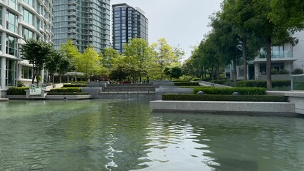 Artificial pond in the city downtown. Peaceful cityscape in the background © Wirestock