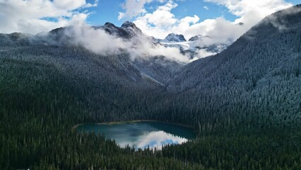 Fototapeta na wymiar View of a round lake surrounded by trees in the mountains in Joffre Lakes Provincial Park