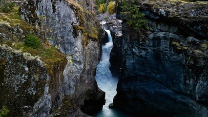 Waterfall in Nairn Falls Provincial Park, Canada, surrounded by rocky mountains and evergreen forest