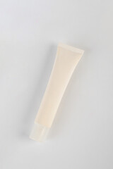 Plastic white tube for cream or lotion. Skin care or sunscreen cosmetic on pink background.