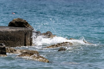 Obraz premium Golden sunrise over the sea waves with stones on the water