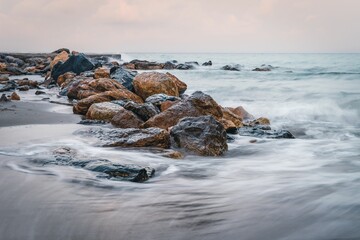 Golden sunrise over the sea waves with stones on the water