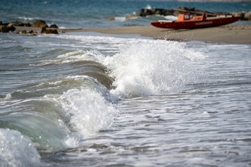 Beautiful seascape of foamy waves hitting the shoreline with rocks