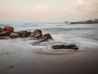 Long exposure effect of ocean waves hitting the sandy beach with stones
