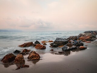 Sea waves calmly hitting a sandy beach with stones