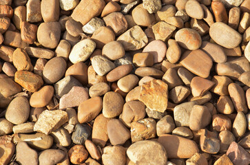 Dry smooth sea (river) stones background, closeup, warm colors