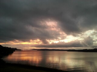 Dramatic clouds and a sunset over a calm body of water