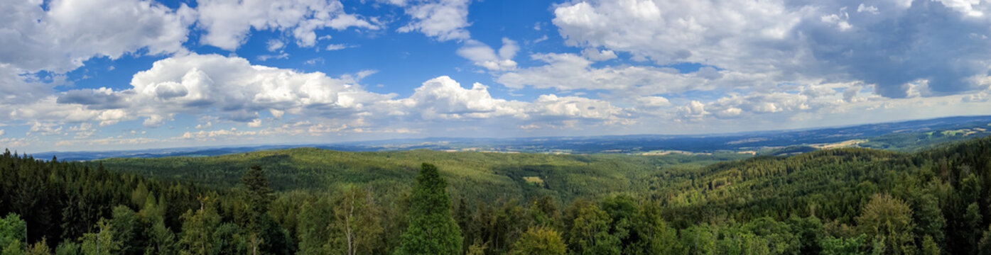 Panoramic view of a green landscape under a cloudy blue sky on a sunny day