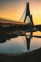 Obraz premium Vertical shot of a beautiful bridge near the sea at sunset