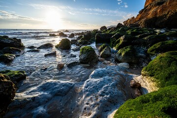 Beautiful view of moss covered stones at the coastline during a sunrise