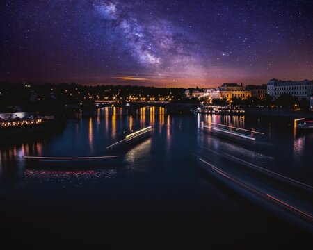 Long exposure photo of Boats on the Vltava river in Prague at night with mesmerizing, starry sky