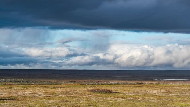 Dark stormy clouds whirl in the sky above the barren landscape of Norwegian tundra.