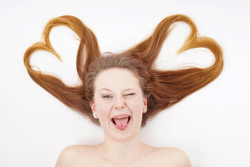 Young woman with hair forming heart shape and winking while sticking out tongue