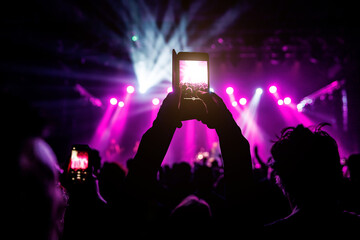 Filming a concert with a mobile phone, music and light show on stage.