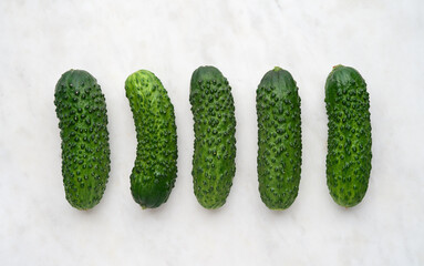 Set of ripe cucumbers on white marble background, top view