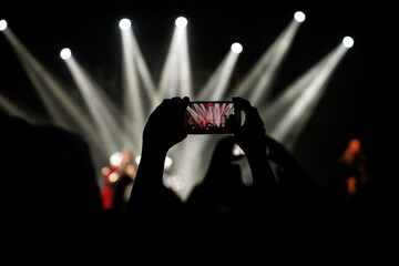 A person capturing a live music concert through their smartphone camera.