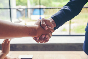 Two businessmen shake hands after success deal and finishing work With Happy corporate Employee and...