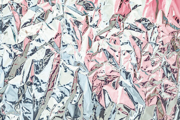 Crumpled metallic foil creating an abstract pattern of pink and silver.