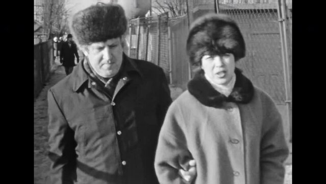 Man, woman portraits in winter clothes, fur hats on street. Adult married couple walk along city outdoors in coats in cold autumn. Nordic 80s fashion. Vintage black white film. archive. Retro 1980s