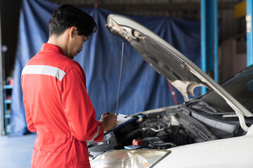 Male mechanic working at garage. Asian male mechanics checks, repair and maintenance under hood of...