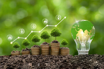 Green energy, eco energy concept. Trees growing on coin stacks symbolize green investments. A graph...