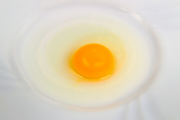 A close up of a yellow quail egg yolk on white plate