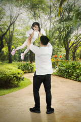Father lifting daughter with blur park background