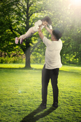 ather lifting daughter with blur tree background